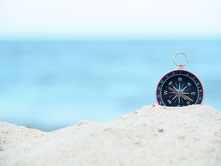 Close up compass on sand.  Sea in soft focus background in Daylight.  Search for navigation of life...