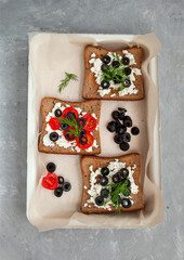 Delicious sandwich with fresh tomatoes, olives and cottage cheese on a grey table background.