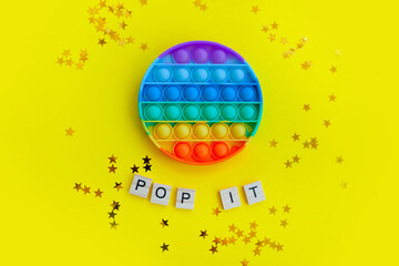 beautiful anti-stress sensory toy fidget push pop it on yellow with stars confetti background - obrazy, fototapety, plakaty