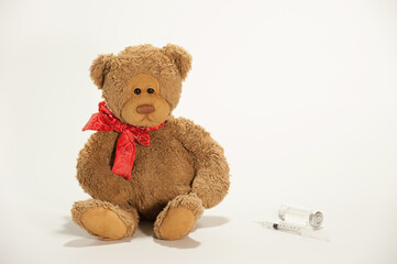 A toy teddy bear with vaccine and syringe for injection on the white background