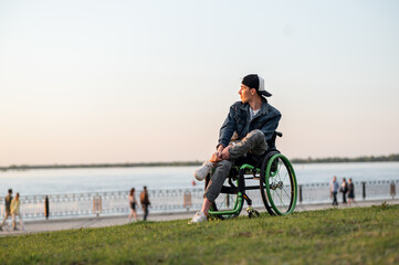 Fototapeta premium a young man in a wheelchair, walking around the city, enjoying the sunset