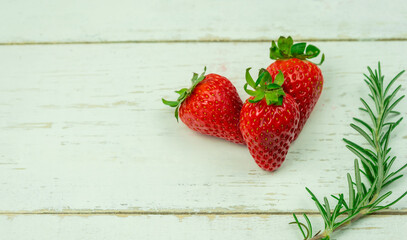 Top view of three strawberries on white wooden background.