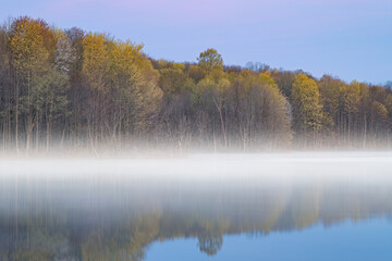 Foggy spring landscape at dawn of the shoreline of Twin Lakes in fog, Michigan, USA