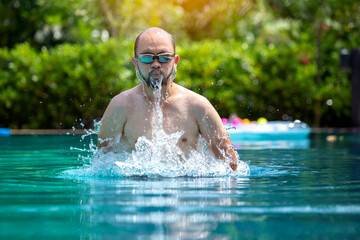 healthy middle-aged man goes for a refreshing swim in the pool. Asian swimmers after exercise Concept for health and lifestyle On the pool background - Powered by Adobe