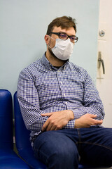 Young man sits in a medical mask to protect against the virus during the COVID-19 coronavirus 