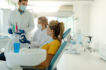 Pretty dentist doctor woman brushing jaw model at dental clinic.