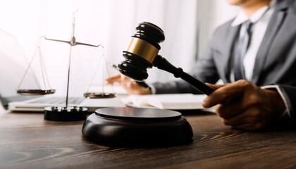 Justice and law concept.Male judge in a courtroom with the gavel, working with, computer and docking keyboard, eyeglasses, on table in morning light
