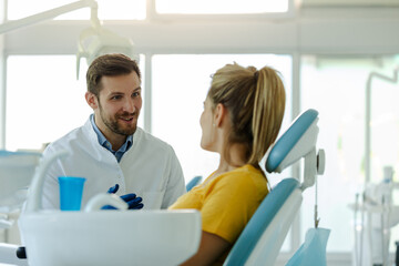 Handsome man dentist talking with his pretty patient.