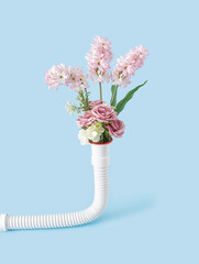 Creative concept of bouquet of fresh flowers coming out of the discharge pipe. Pastel blue...