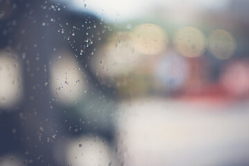 Window with raindrops and blurred lights in background