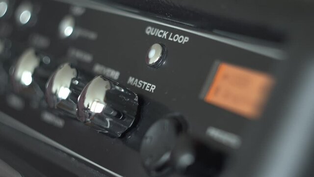 Rock Musician Adding Master Volume On Guitar Amplifier. Music and performance concept video.