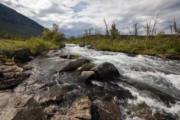 Fast mountain river under a cloudy sky in polar Sweden