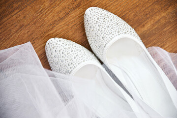 white bride shoes and veil on wooden background. shallow depth of field