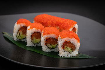 Japanese cuisine. Rolls on a black plate on a wooden table
