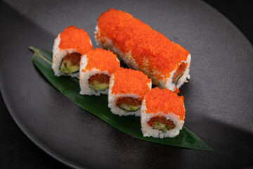 Japanese cuisine. Rolls on a black plate on a wooden table
