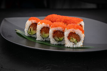 Japanese cuisine. Rolls on a black plate on a wooden table

