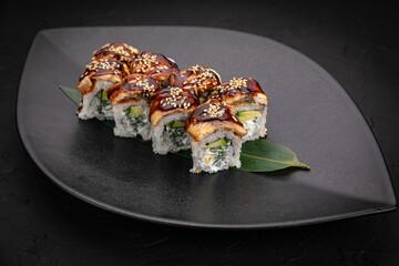 Japanese cuisine. Rolls on a black plate on a wooden table
