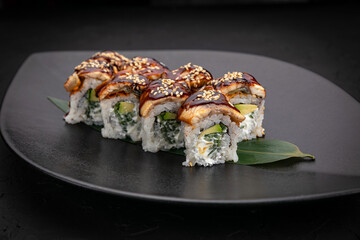 Japanese cuisine. Rolls on a black plate on a wooden table
