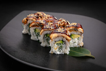 Japanese cuisine. Rolls on a black plate on a wooden table
