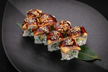 Japanese cuisine. Rolls on a black plate on a wooden table
