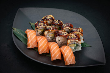 Japanese cuisine. Rolls on a black plate on a wooden table

