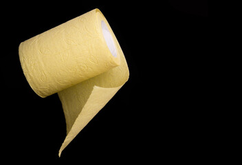 Roll of yellow toilet paper on black background close up