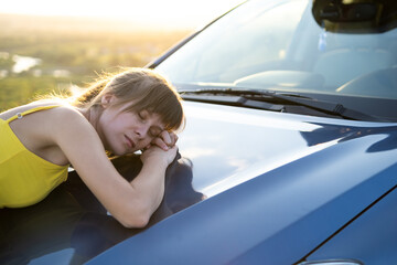 Carefree woman driver in yellow summer dress enjoying warm evening near her car.