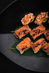 Japanese cuisine. Rolls on a black plate on a wooden table