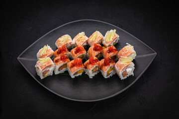 Japanese cuisine. Rolls on a black plate on a wooden table