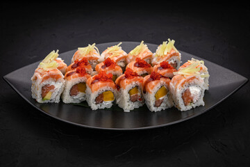 Japanese cuisine. Rolls on a black plate on a wooden table