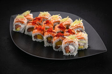 Japanese cuisine. Rolls on a black plate on a wooden table