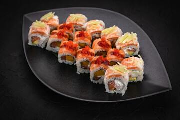 Japanese cuisine. Rolls on a black plate on a wooden table