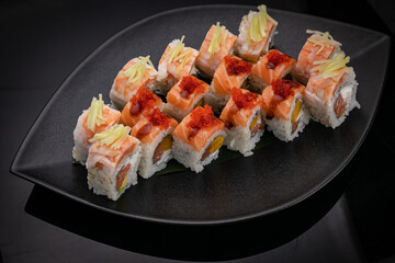 Japanese cuisine. Rolls on a black plate on a wooden table