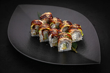 Japanese cuisine. Rolls on a black plate on a wooden table
