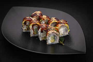 Japanese cuisine. Rolls on a black plate on a wooden table