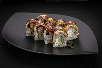 Japanese cuisine. Rolls on a black plate on a wooden table