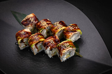 Japanese cuisine. Rolls on a black plate on a wooden table