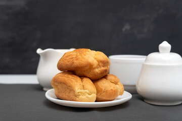 Homemade profiteroles on table on gray background. Puffs, popovers. Traditional French eclairs