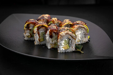 Japanese cuisine. Rolls on a black plate on a wooden table