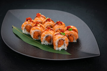 Japanese cuisine. Rolls on a black plate on a wooden table