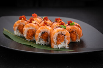 Japanese cuisine. Rolls on a black plate on a wooden table