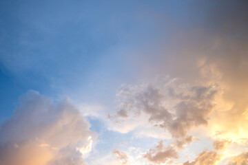 Fototapeta na wymiar Dramatic sunset sky landscape with puffy clouds lit by orange setting sun and blue heavens.