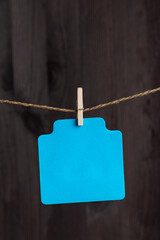 Blank blue paper card hang with clothespin on rope. Copy space. Place for your text. Vertical frame