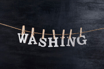 Word WASHING with clothespins on black background. Concept of laundry service.