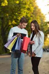Young couple is looking at their purchases with interest. Colored paper bags in hands