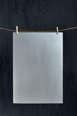 Gray paper sheet hanging with clothespins on rope. Place for your text. Copy space, mockup. Vertical frame