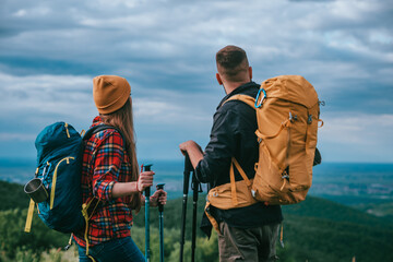 Couple of hikers using trekking poles and wearing backpacks