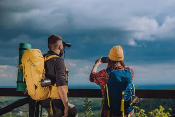 A couple of hikers taking picture with a samrtphone and using binoculars