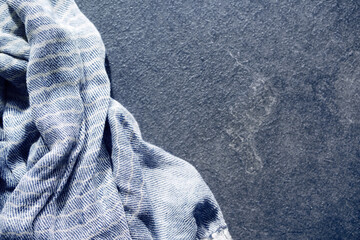 Abstract background with draped blue-gray cotton cloth, napkin, striped tablecloth or scarf on dark...