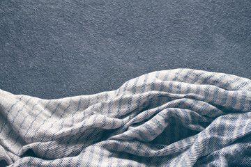 Abstract background with draped blue-gray cotton cloth, napkin, striped tablecloth or scarf on dark...